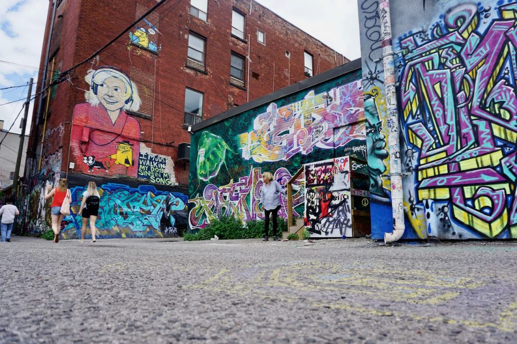A low angle shot of graffiti alley with tourists walking by